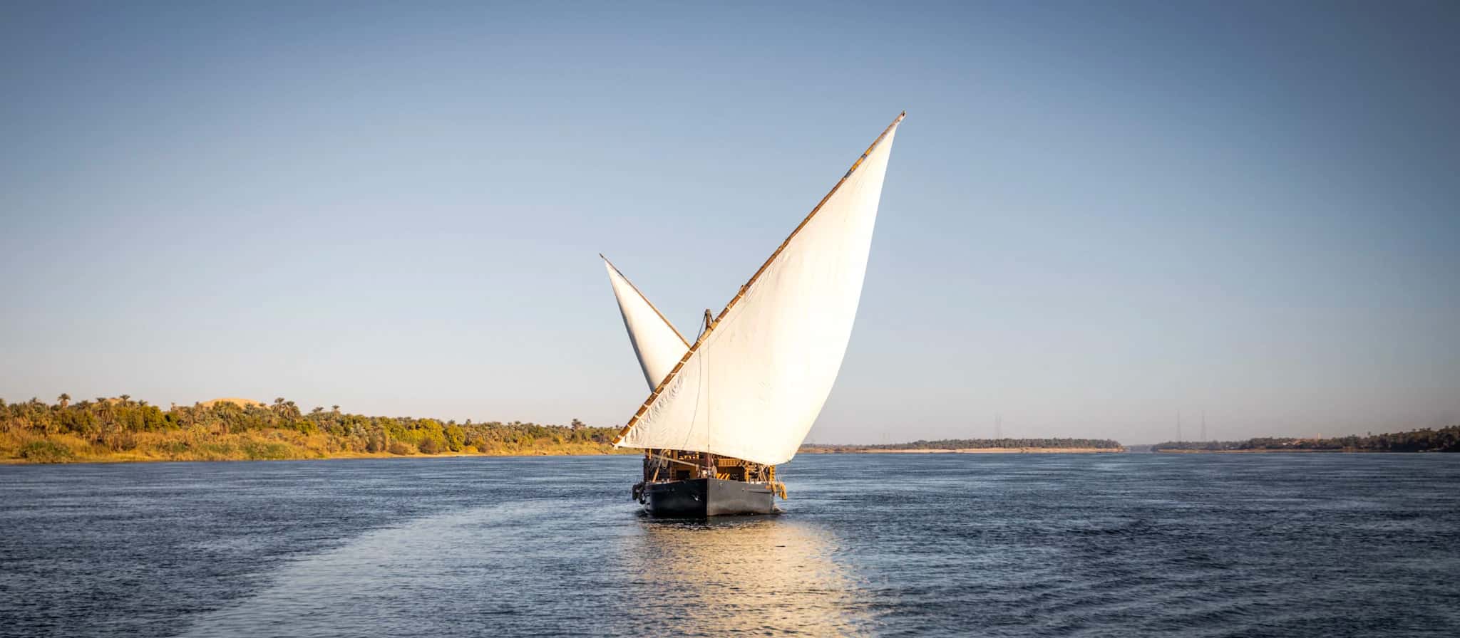 Navegando en un velero tradicional por aguas tranquilas Globos aerostáticos flotando sobre formaciones rocosas en Capadocia, Turquía, al amanecer.