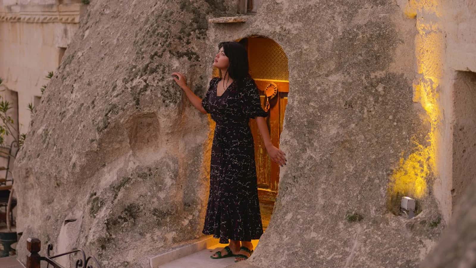 Despertar en un hotel cueva en Capadocia Mujer saliendo de una habitación cueva en Capadocia iluminada al amanecer