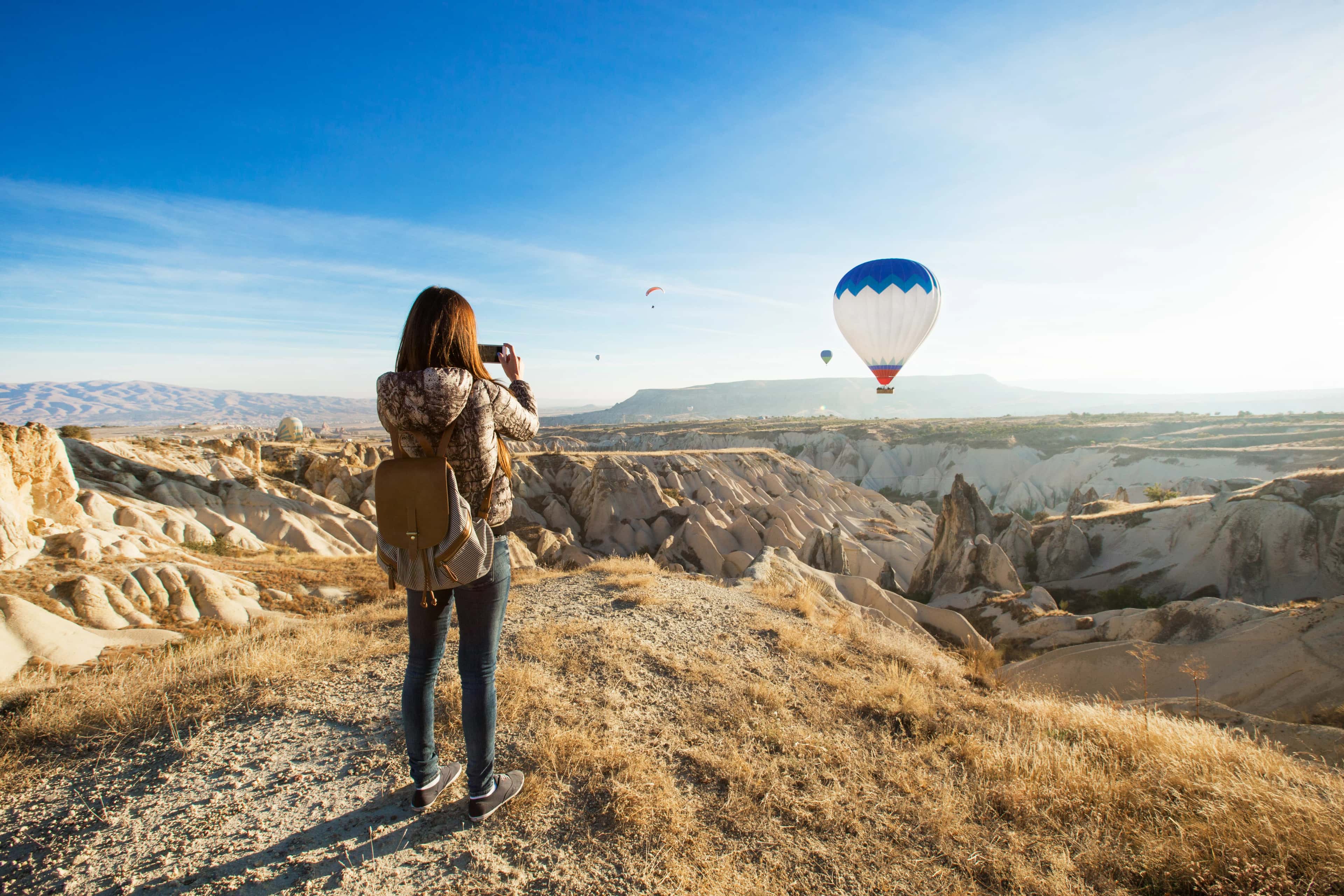 Viajera contemplando los valles de Capadocia al amanecer con globos aerostáticos, una experiencia cultural y sensorial en Turquía Capadocia al amanecer: contemplar el paisaje desde el silencio
